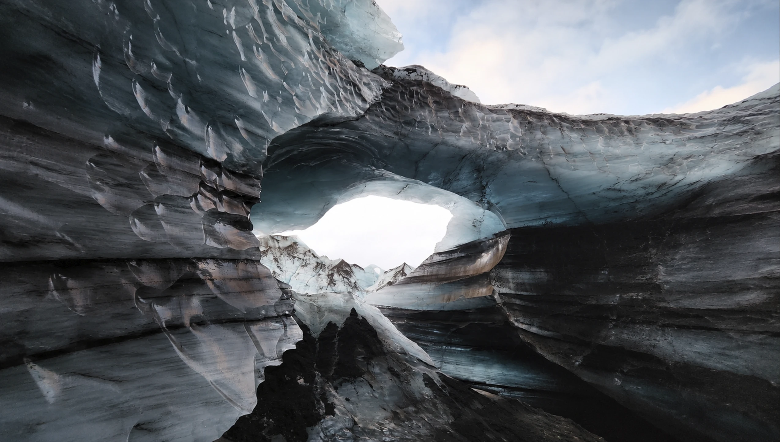 Cueva de hielo de Katla en Islandia con formaciones glaciales y apertura hacia montañas