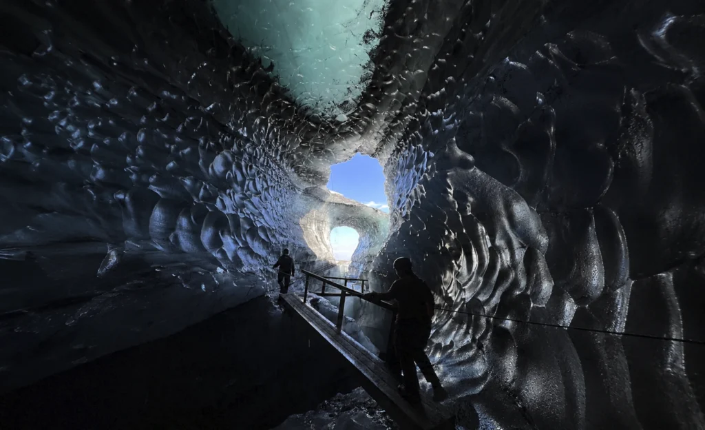 Interior de cueva de hielo en Katla con pasarela y personas explorando el glaciar