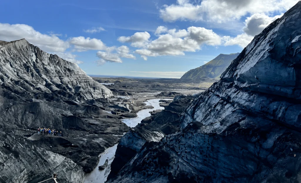 Glaciar Katla en Islandia con río glaciar y excursionistas caminando sobre hielo volcánico