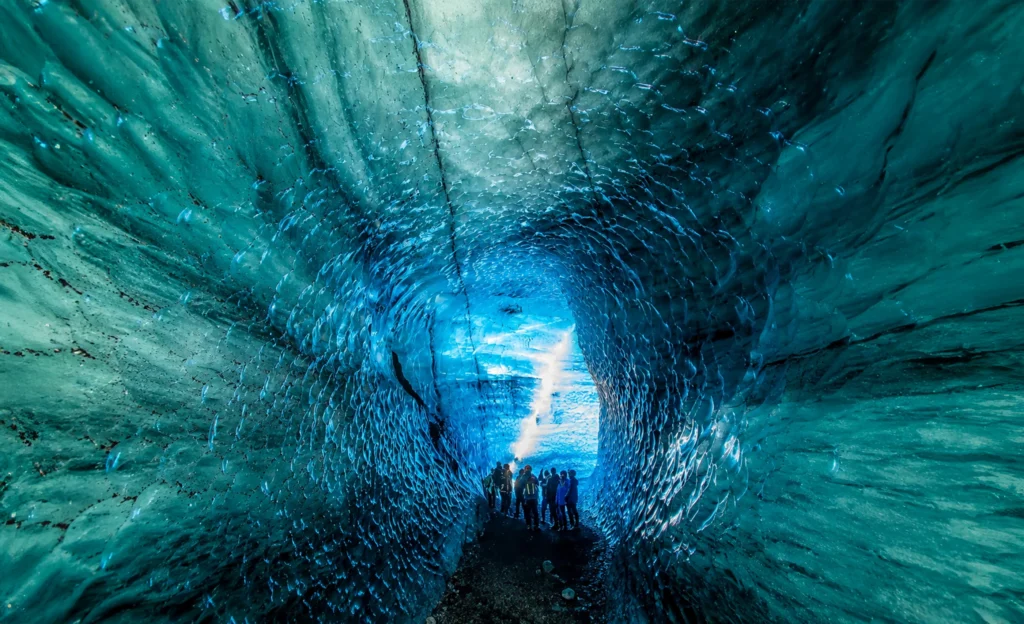 Interior de cueva de hielo azul en Katla Islandia con grupo de turistas explorando