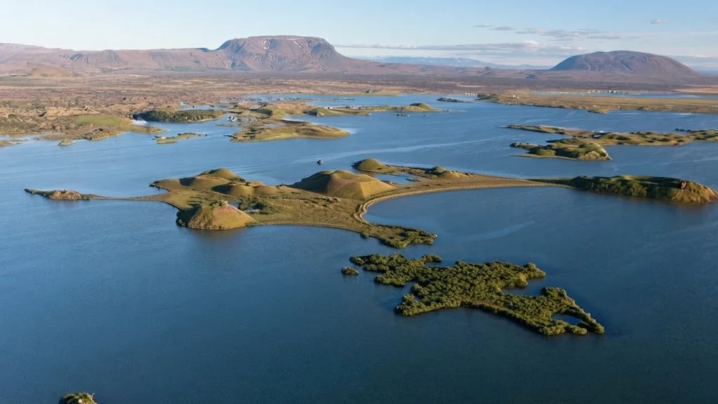 Islotes y pseudocráteres en el lago Mývatn con paisaje volcánico y montañas al fondo en Islandia