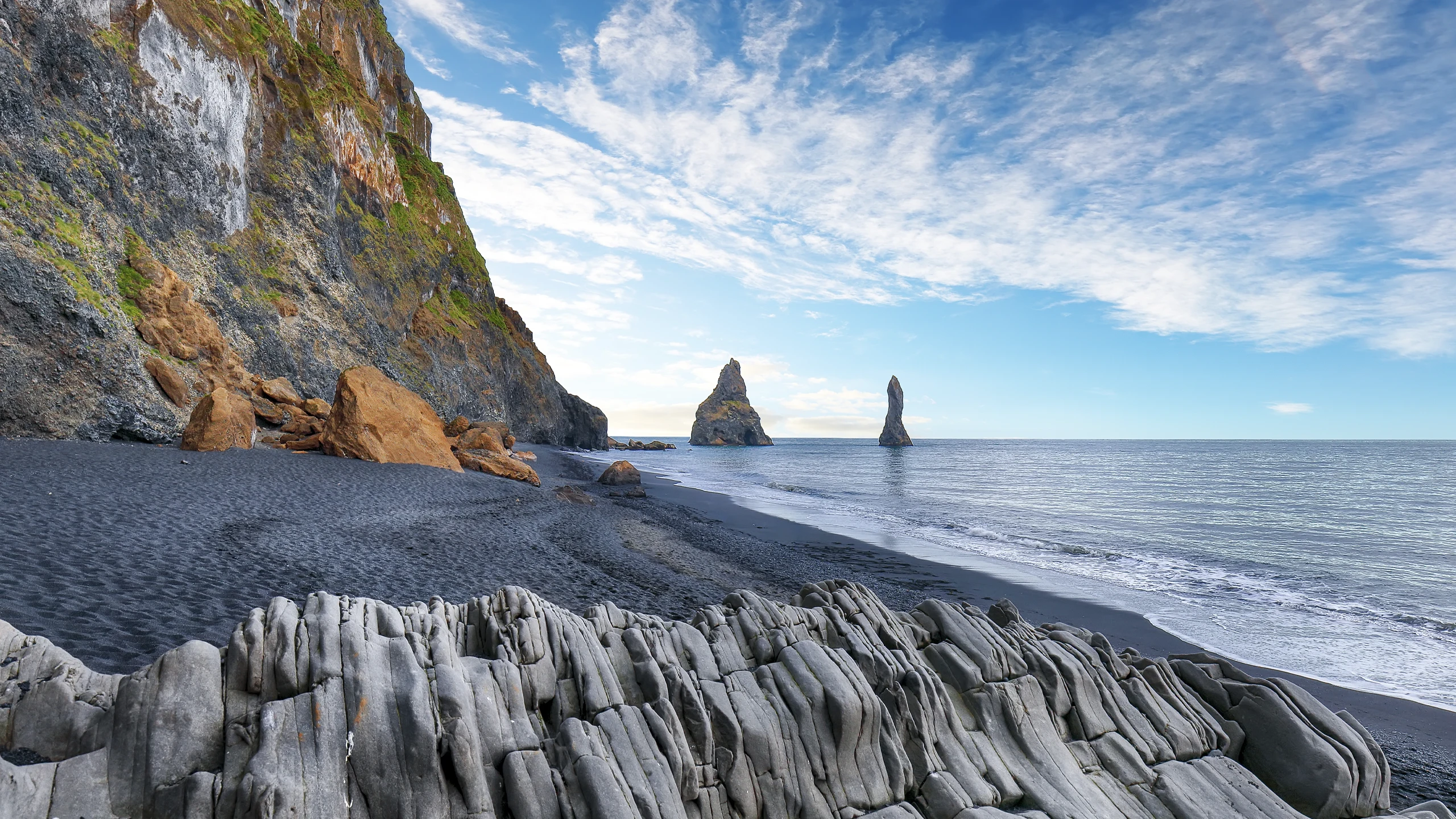 Playa de Reynisfjara con arena negra, columnas de basalto y formaciones rocosas en el mar en Islandia