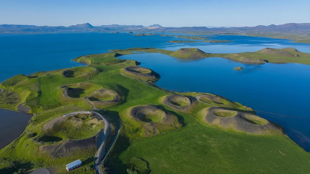 Pseudocráteres del lago Mývatn con colinas verdes y paisaje volcánico junto al agua en Islandia