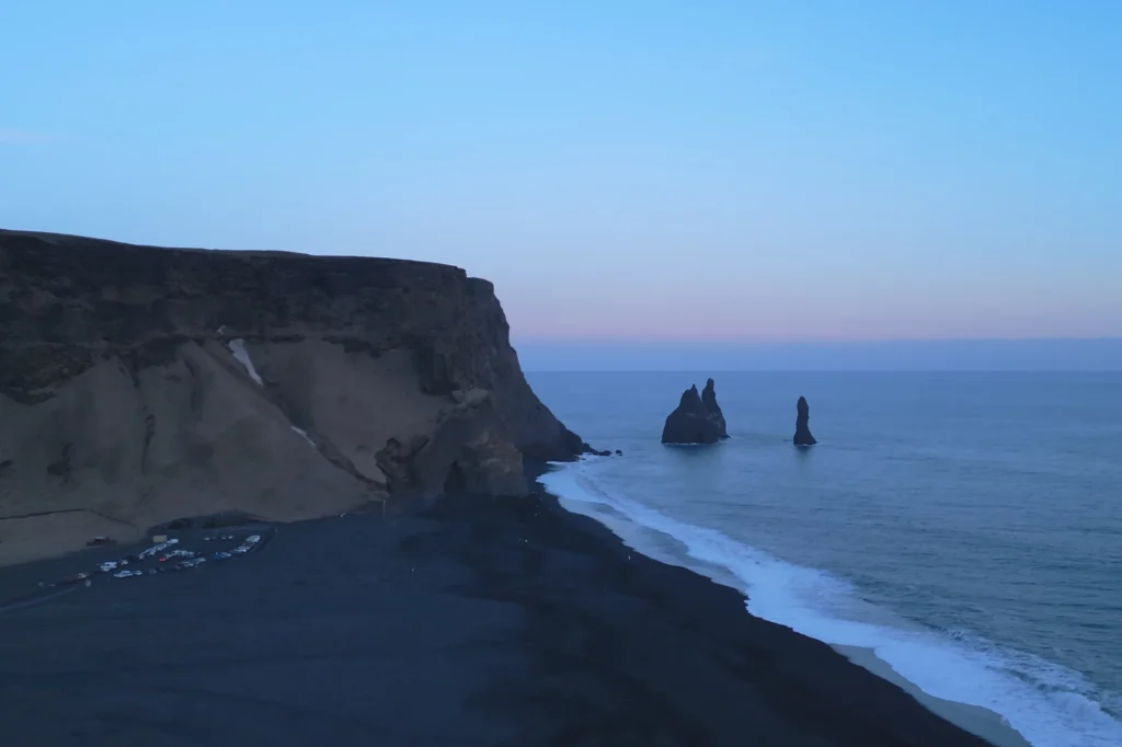 Vista aérea de la playa de Reynisfjara con acantilados y farallones Reynisdrangar al atardecer en Islandia