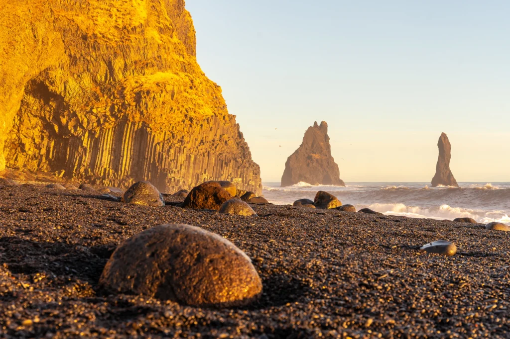 Playa de Reynisfjara con columnas de basalto y farallones Reynisdrangar al atardecer en Islandia