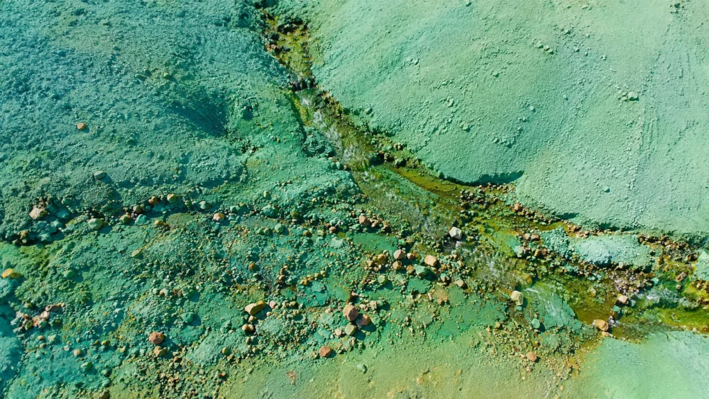 Vista aérea de un arroyo entre terrenos verdes y rocosos de Grænihryggur, en Islandia.