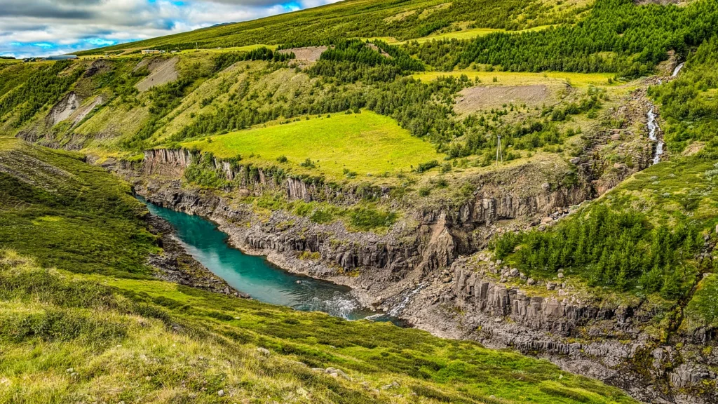 Vista panorámica del cañón Stuðlagil con río turquesa y paisaje verde en Islandia
