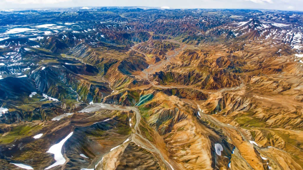 Vista aérea de Grænihryggur en Islandia, con montañas multicolores, valles y zonas de nieve.