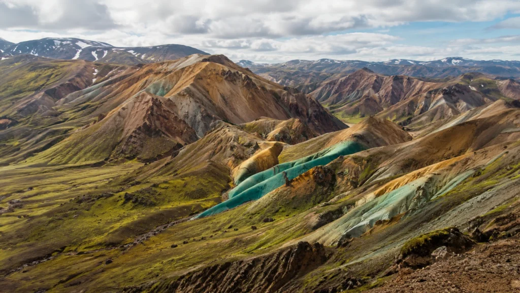 Vista panorámica de las montañas multicolores de Grænihryggur, en Islandia, con laderas verdes, ocres y turquesas.