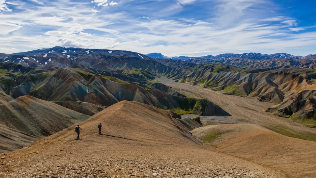 Dos senderistas recorren una cresta con vistas a las montañas multicolores de Grænihryggur, en Islandia.