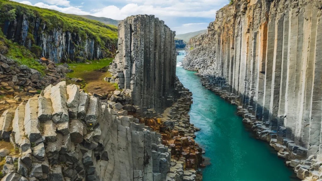 Cañón Stuðlagil con columnas de basalto y río turquesa entre formaciones volcánicas en Islandia