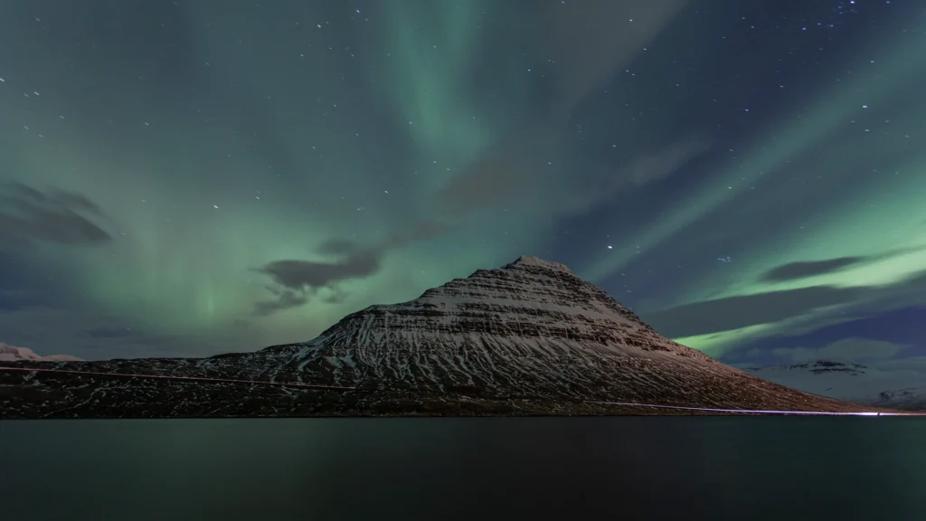 Aurora boreal verde sobre una montaña nevada junto al agua en Islandia