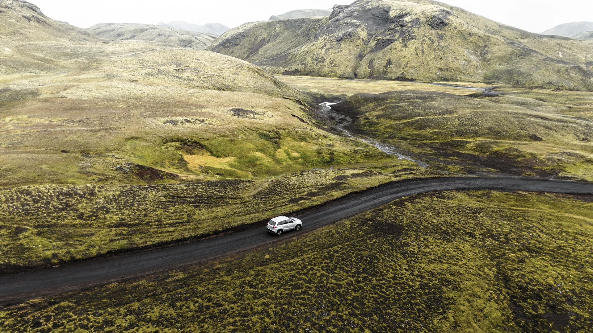 Coche 4x4 recorriendo una carretera de grava entre montañas de Islandia