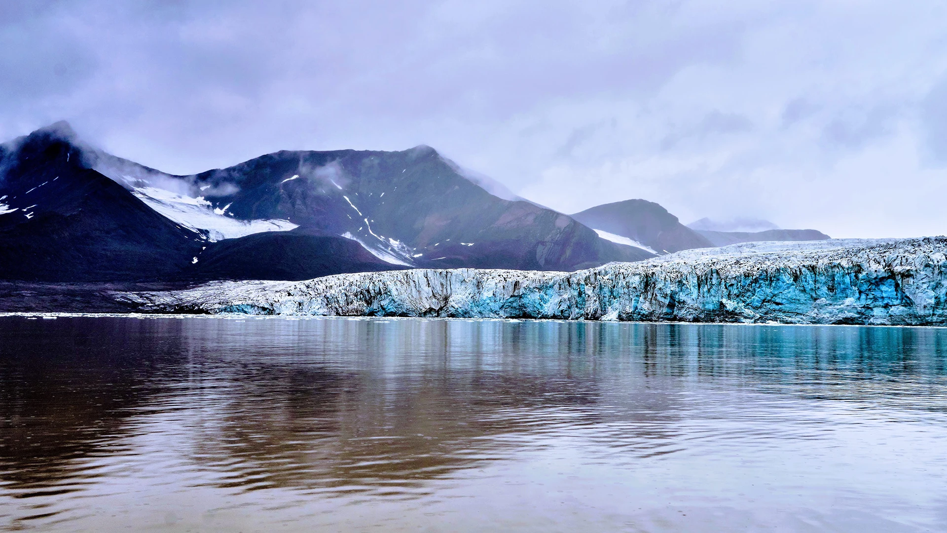 Lengua glaciar junto a una laguna en Islandia, con montañas al fondo.