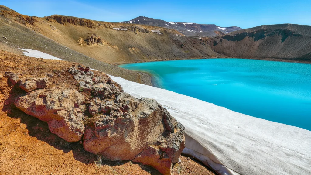 Lago turquesa del cráter Víti en Krafla con nieve y rocas volcánicas en el norte de Islandia