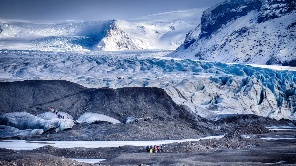 Excursionistas caminan sobre un glaciar de Skaftafell, entre grietas, hielo azul y morrenas oscuras.