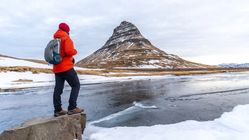 Dos visitantes contemplan las paredes de hielo con chaquetas, pantalón largo y cascos. La imagen puede acompañar la guía sobre qué ropa llevar a Islandia en el apartado sobre las excursiones a glaciares y cuevas de hielo.